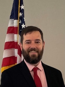 Professional headshot of Commissioner Conway in front of the American flag
