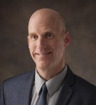 Photo of Chris Downey in a navy suit