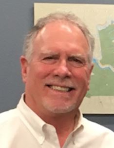 commissioner holloway, white button up shirt, map on wall in background