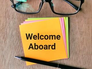 Picture of Sticky notes saying "Welcome Aboard" with a pen on top of the sticky notes and a pair of reading glasses above.