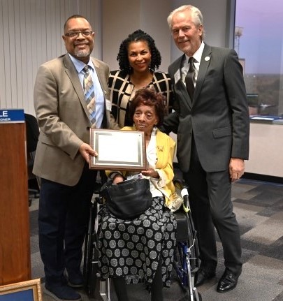 Picture of former Commissioner Betty Wilson receiving an award with 3 people standing behind her.