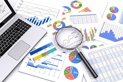 Laptop computor with charts and maginifying glass