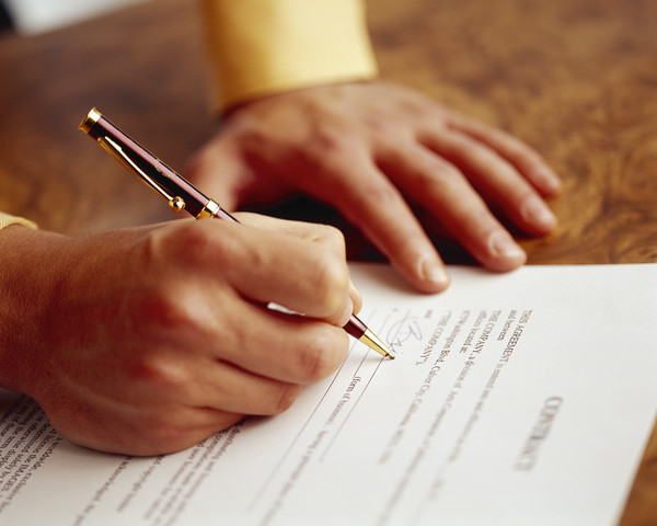 A hand signing a contact paper