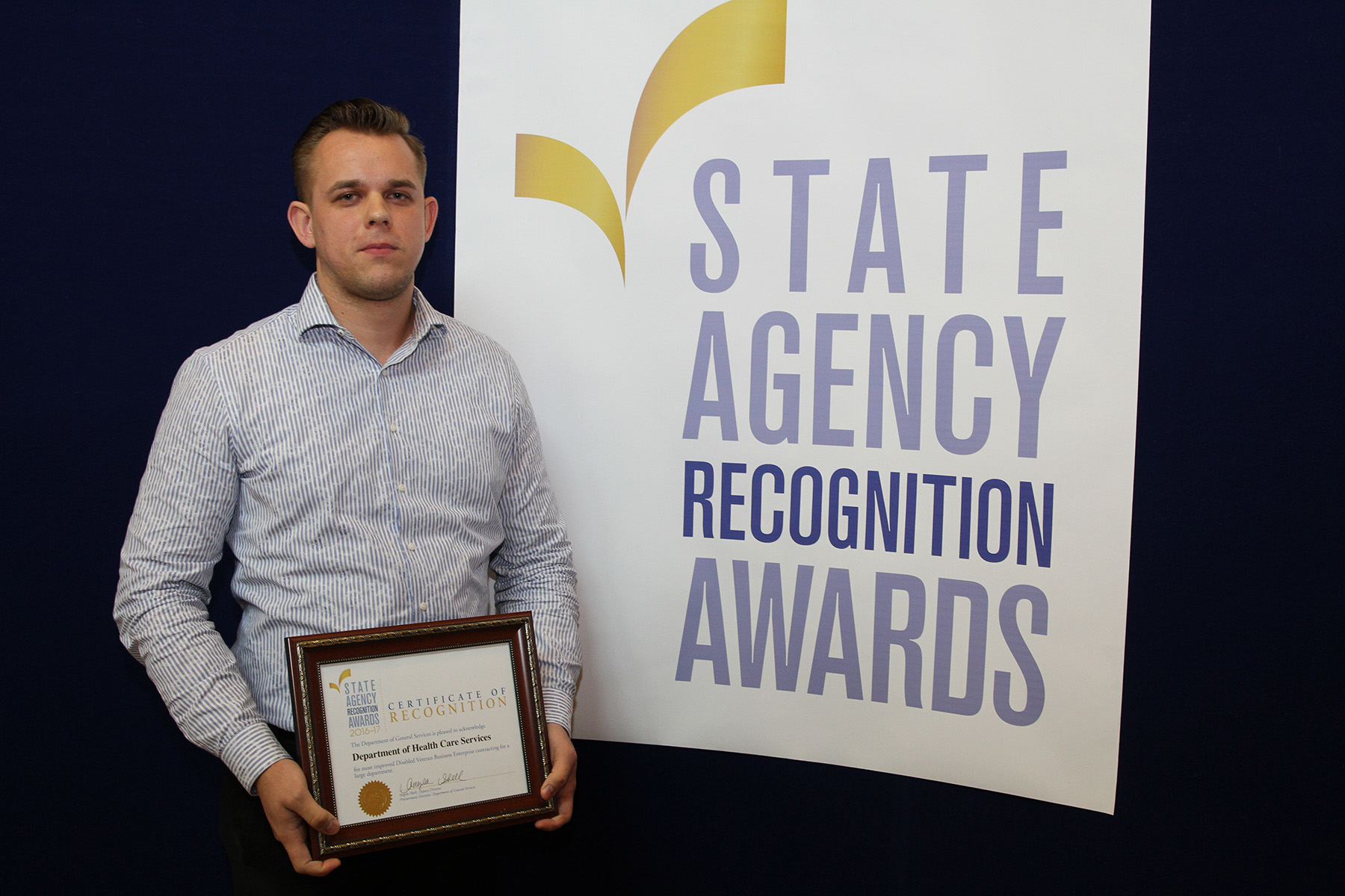 Max Lyulkin accepts the most improved small business participation award for the Department of Health Care Services for the large agency category