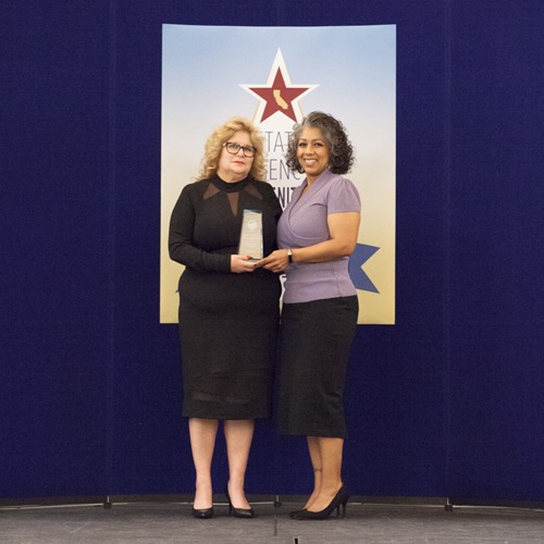 Nina Martinez accepts the gold advocate of the year award on behalf of Eleanor Amith.