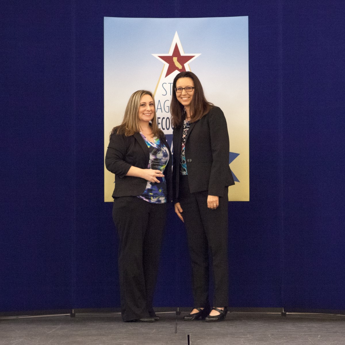 Sarah Ward accepts the employee of the year award, presented by Angela Shell, Deputy Director, Procurement Division, Department of General Services.