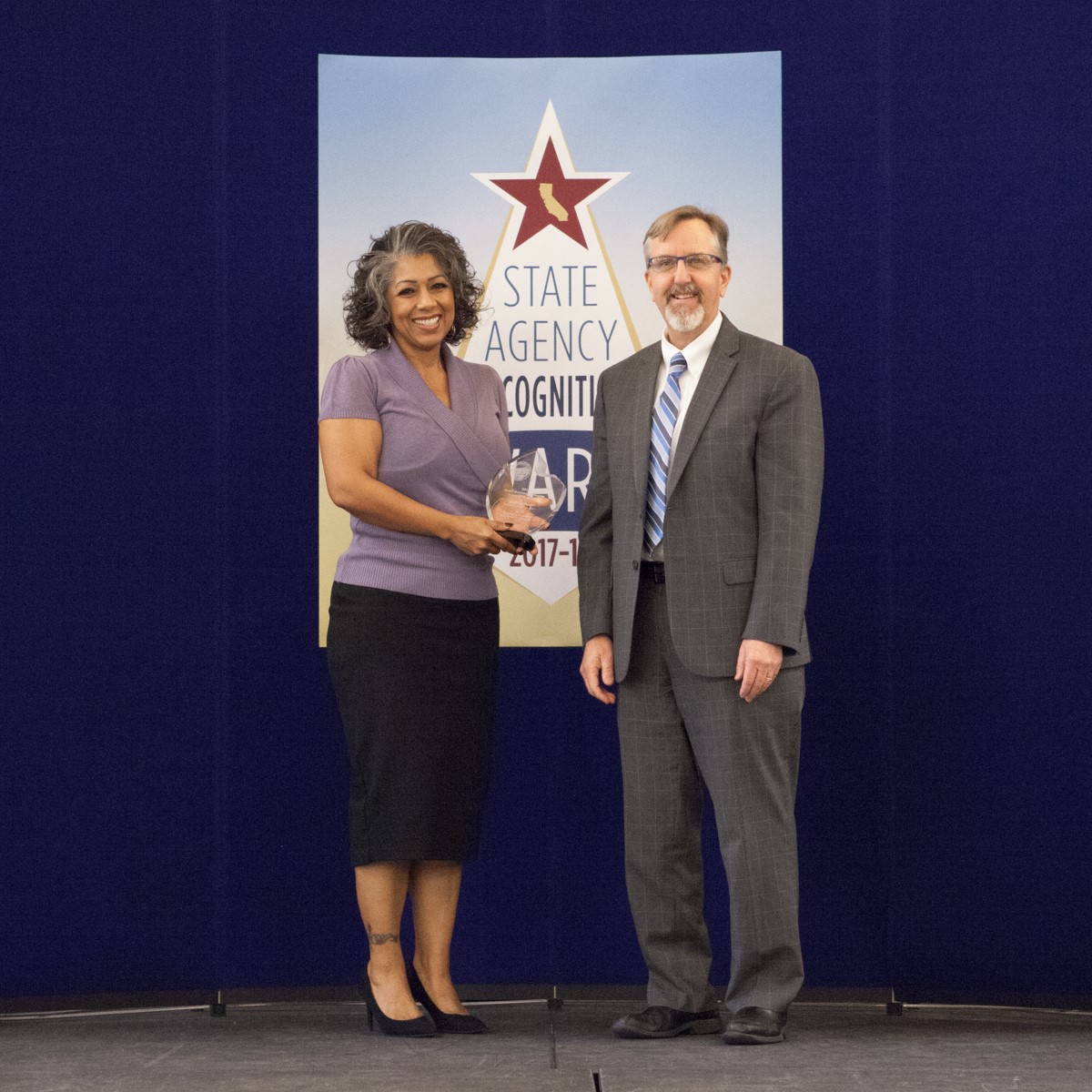 Andrea Pina accepts the small business advocate innovation award, presented by Jeff McGuire, Chief Deputy Director, Department of General Services