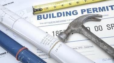 Building permit with hammer and plans on a table
